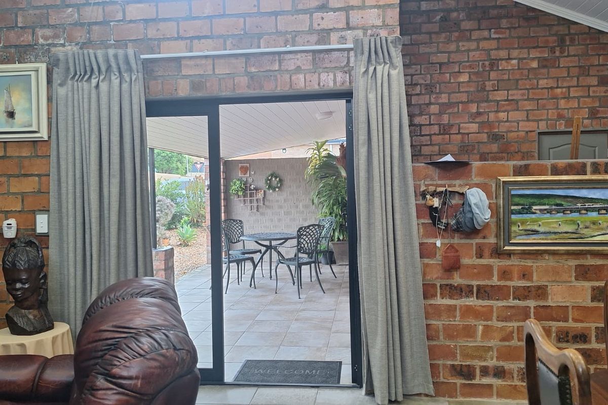 Living room featuring exposed brick walls and a sliding glass door providing direct access to an outdoor patio area.
