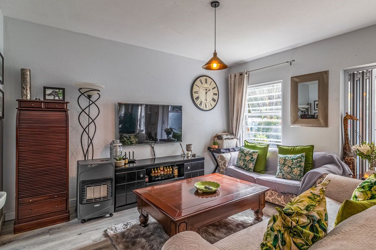 A cozy living room featuring laminate flooring, a central pendant light, and bi-fold doors providing access to the outdoor area.