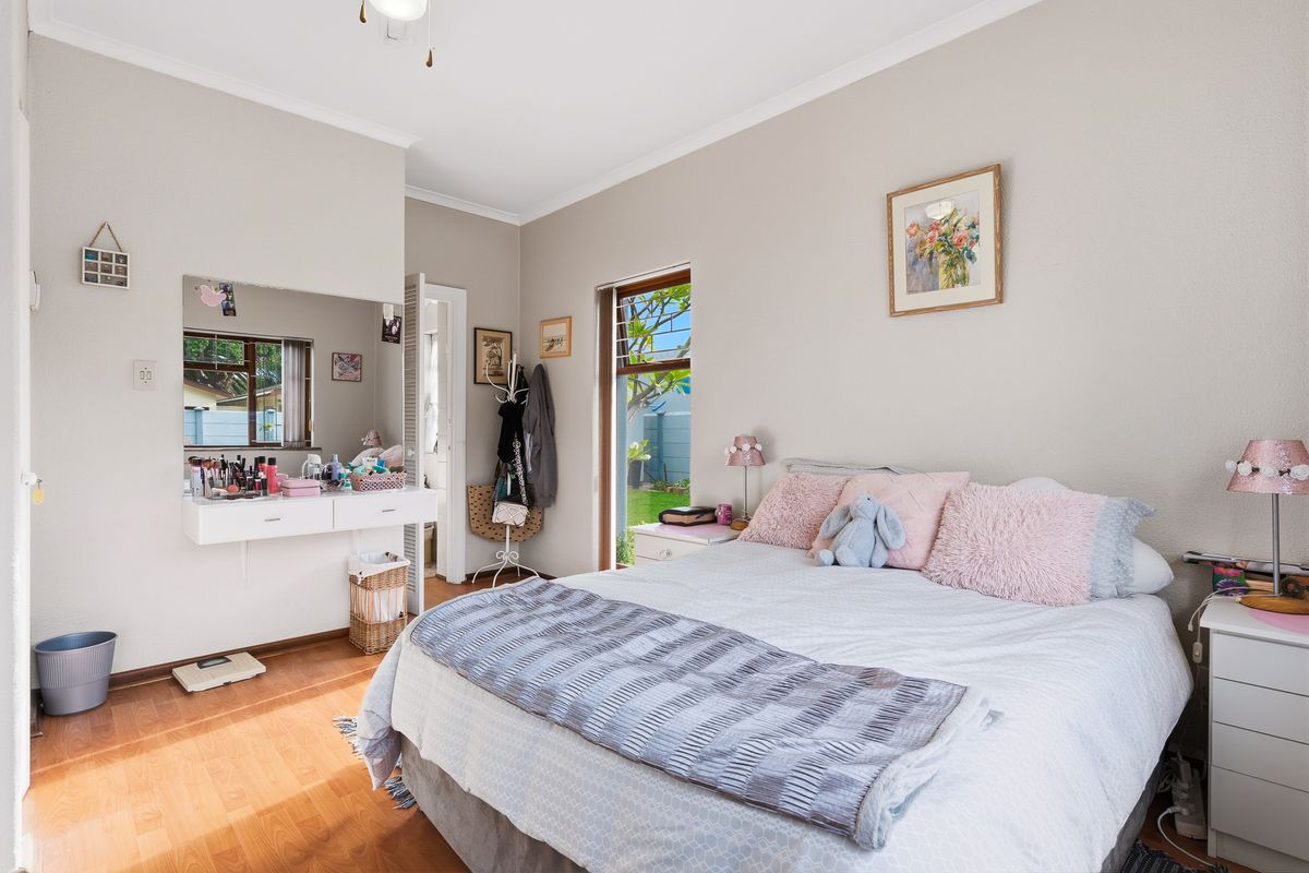 A well-lit bedroom featuring laminate flooring, a built-in vanity unit, and direct access to the garden through a sliding door.