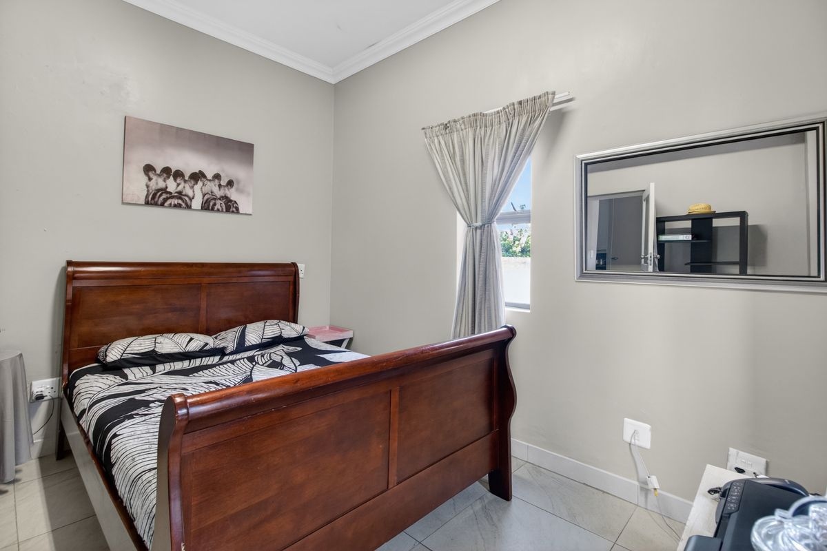A bedroom featuring neutral wall paint, tiled flooring, and decorative cove cornicing, providing a clean and functional living space.