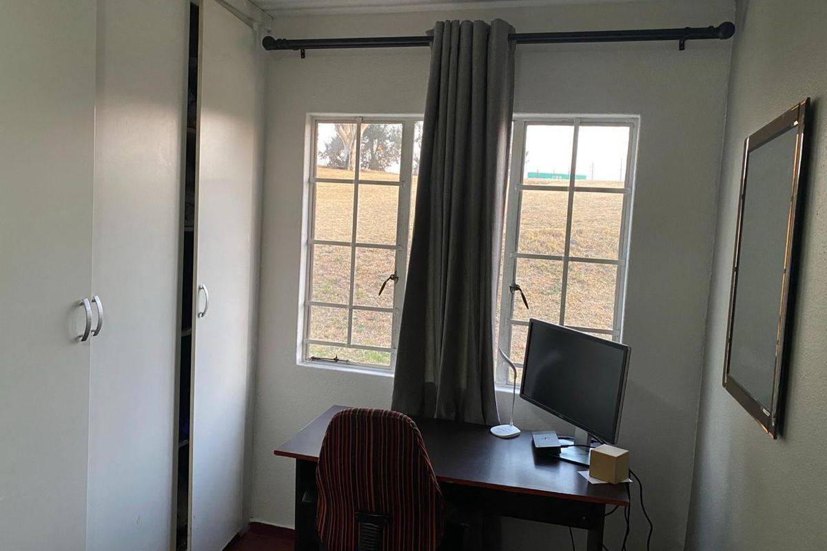 A functional bedroom featuring built-in wardrobes and classic casement windows, offering a practical space suitable for a bedroom or home office setup.