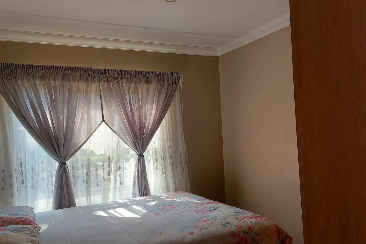 A bedroom featuring neutral wall tones, a built-in wardrobe, and decorative cove cornicing, providing a functional and comfortable sleeping space.