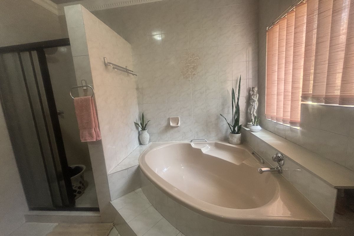 A bathroom featuring a built-in bathtub, separate shower enclosure, and tiled finishes, offering a functional layout with potential for modern updates.