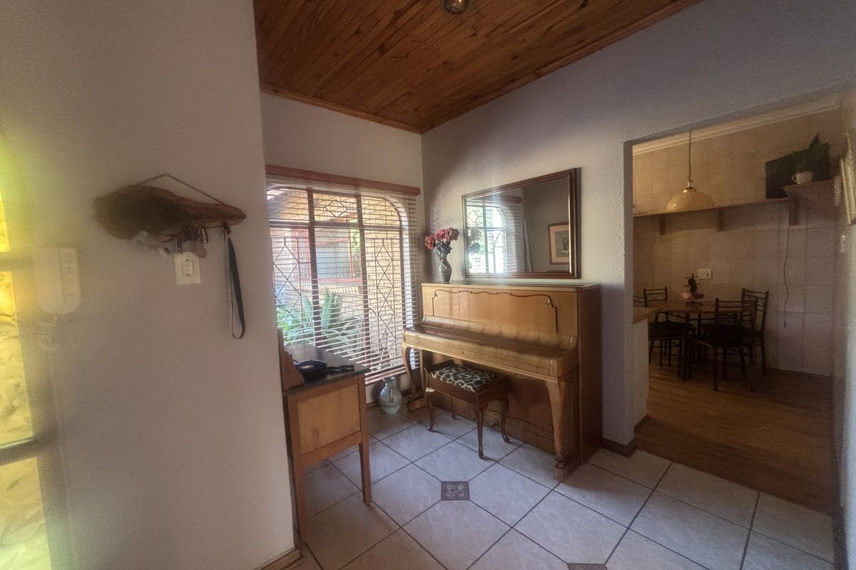 A living area featuring ceramic floor tiles and a warm timber tongue and groove ceiling, with an open transition to the adjacent dining space.