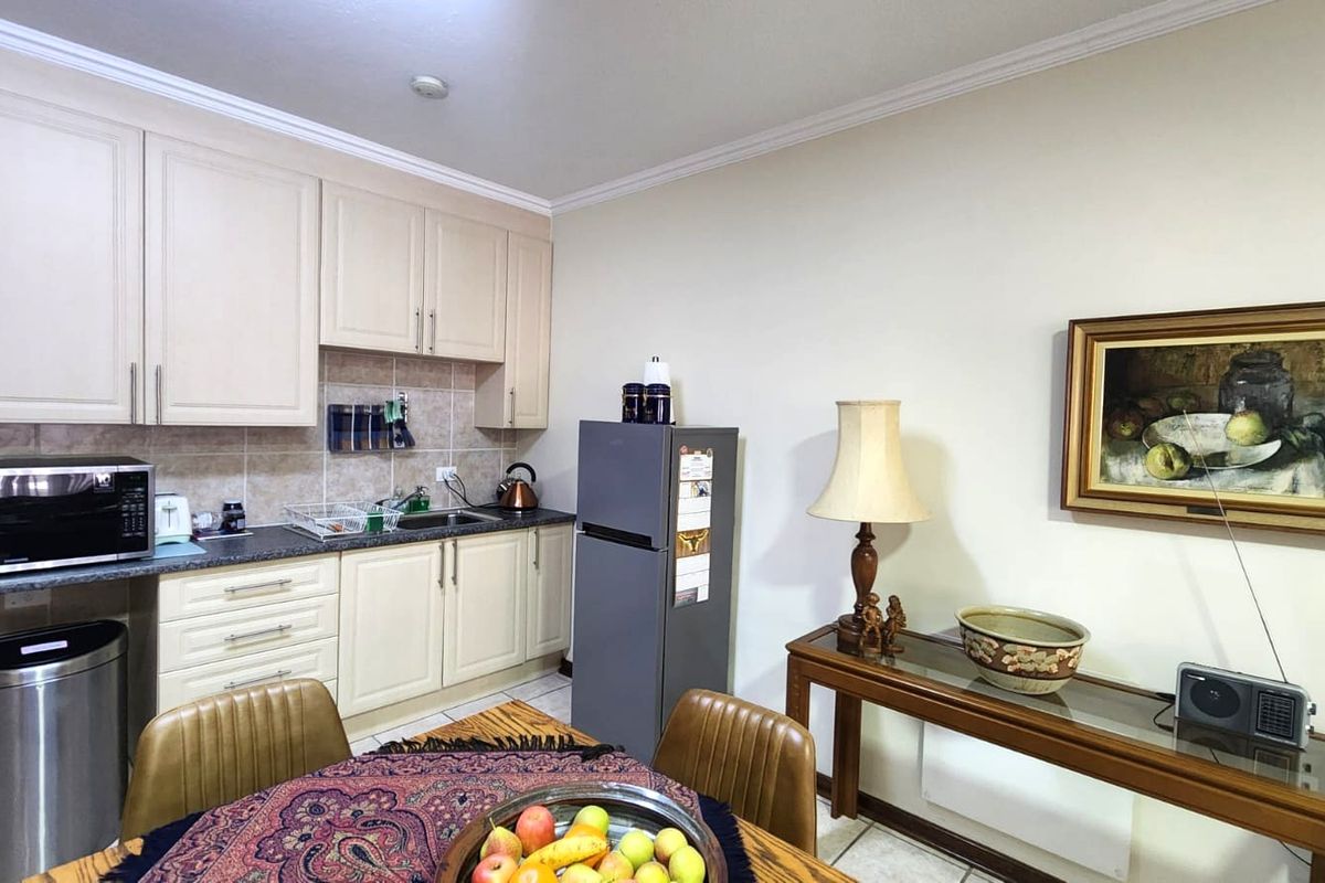 A functional kitchen featuring cream-colored cabinetry, laminate countertops, and a tiled backsplash, providing a practical workspace within the apartment.