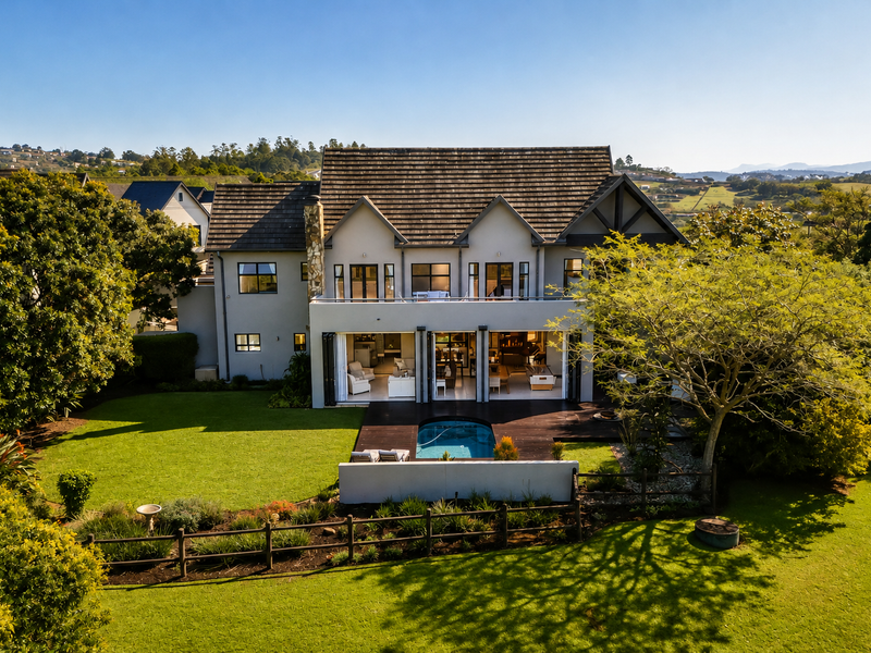 Rear view of a luxury townhouse featuring a swimming pool, timber decking, and expansive bi-fold doors opening to a landscaped garden.