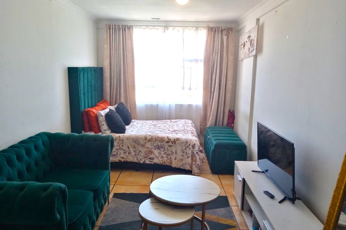 A compact bedroom featuring tiled flooring and cove cornice detailing, currently utilized as a multi-functional living and sleeping space.