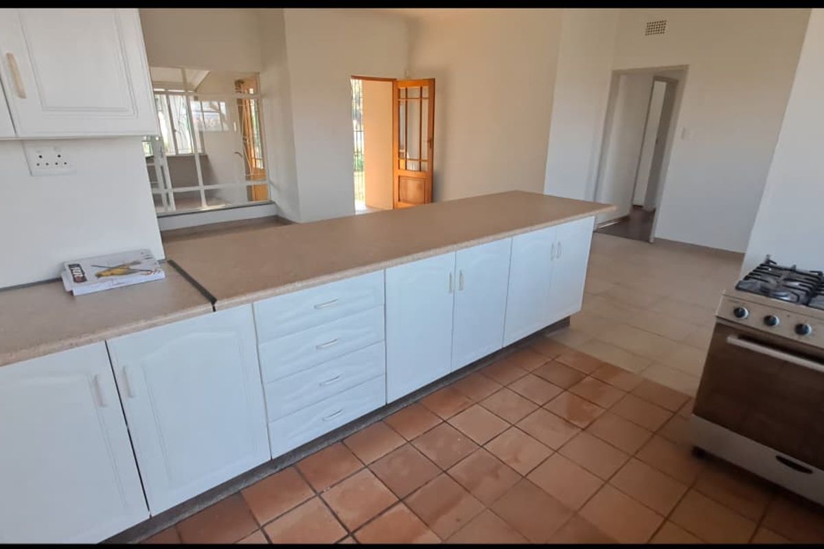 A spacious kitchen featuring white built-in cabinetry, a gas stove, and tiled flooring, offering a functional layout with potential for modern updates.