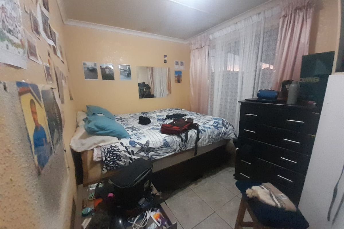 A compact bedroom featuring tiled flooring and standard ceiling finishes, offering a functional space that could benefit from cosmetic updates.