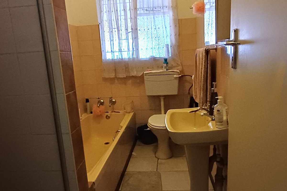 A dated bathroom featuring a pedestal basin, bathtub, and toilet with original tiling, requiring modernization to improve aesthetic appeal and functionality.