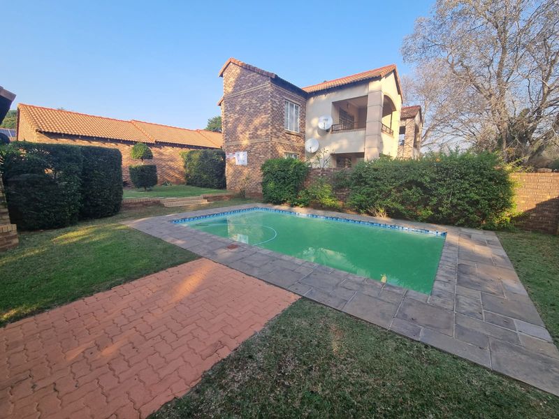 A private swimming pool area set within a landscaped garden, featuring brick paving and views of the townhouse exterior facade.