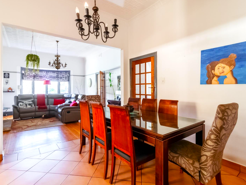 Open plan dining and living area featuring a combination of tiled and hardwood flooring, classic chandeliers, and timber-framed glass doors.
