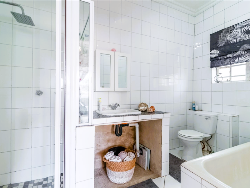 A functional bathroom featuring a shower, bathtub, toilet, and a vanity basin with exposed plumbing and unfinished base cabinetry.
