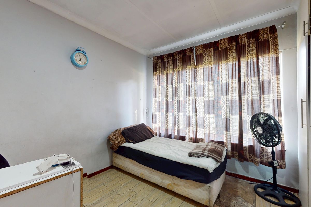 A compact bedroom featuring tiled flooring and a built-in wardrobe, offering a functional space ready for cosmetic updates.