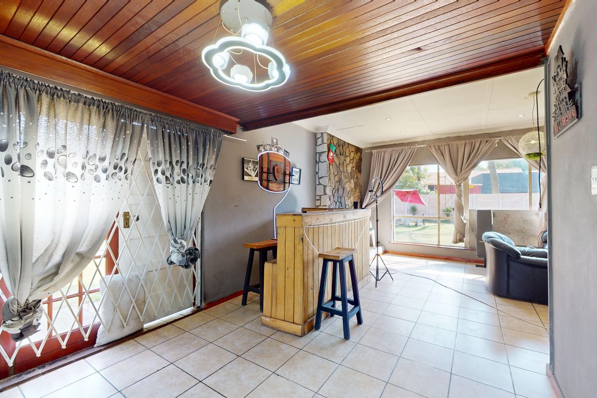 Living area featuring a timber-clad ceiling, stone-clad feature wall, ceramic floor tiles, and a built-in bar, with direct access to the garden.