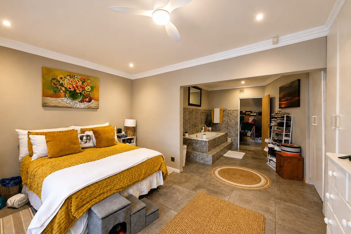 Spacious bedroom featuring tiled flooring, crown molding, and an integrated en-suite bathroom area with a built-in bathtub and recessed lighting.