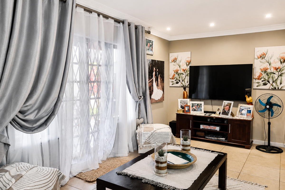 A well-maintained living room featuring ceramic floor tiles, recessed downlighting, and a sliding glass door with an integrated security gate.