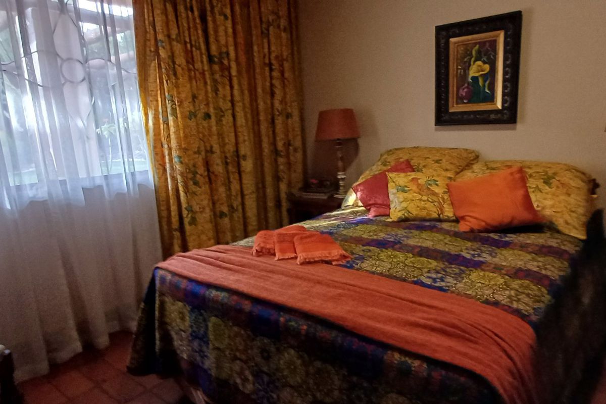 A cozy bedroom featuring tiled flooring and a large window with natural light, providing a comfortable and functional sleeping space.