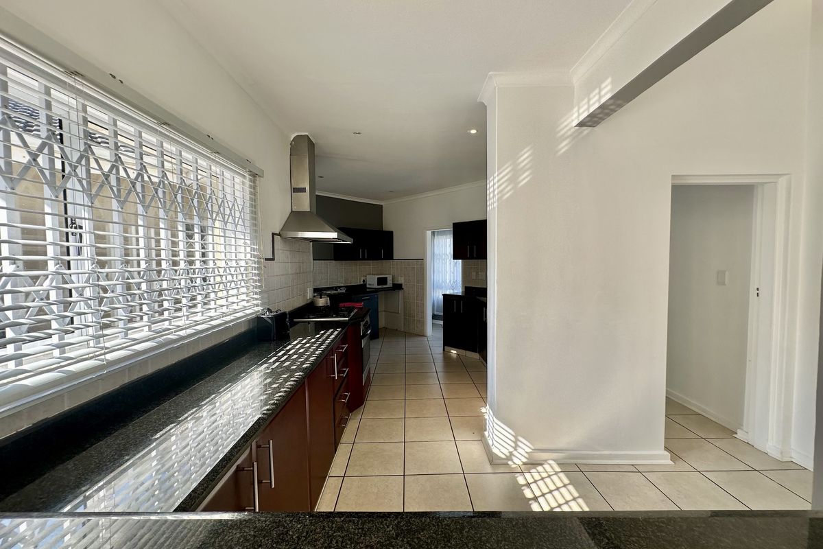 A functional kitchen featuring dark cabinetry, granite countertops, and ceramic floor tiles, offering a clean and practical layout for culinary activities.