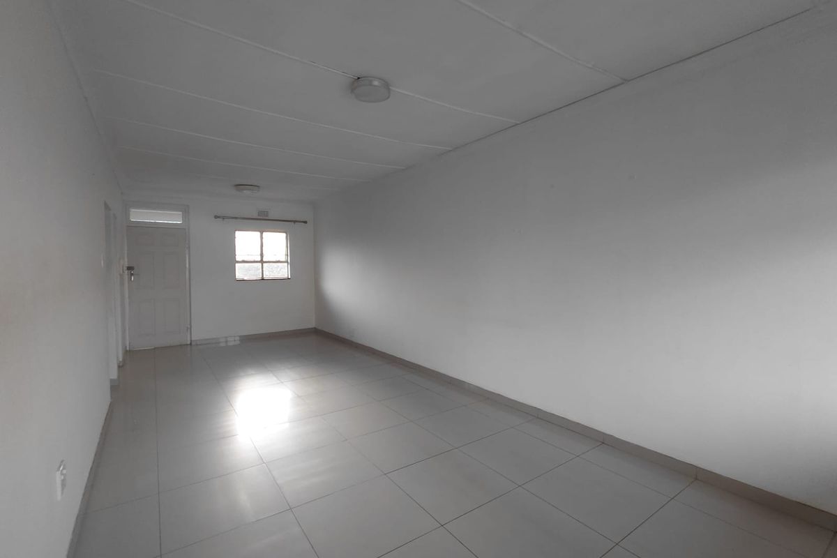 A spacious, empty living area featuring neutral tiled flooring and clean white walls, offering a blank canvas for interior design.