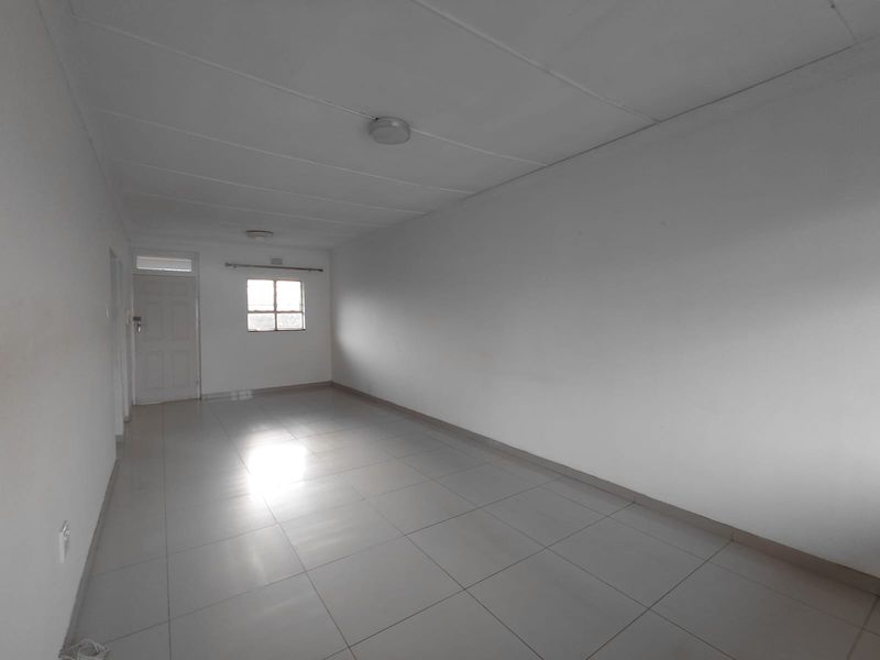 A spacious, empty living area featuring neutral tiled flooring and clean white walls, offering a blank canvas for interior design.