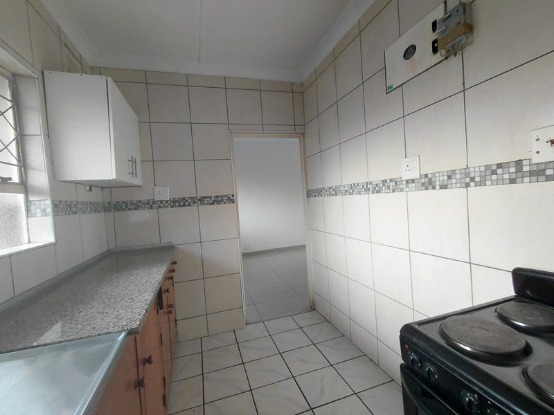 A functional kitchen featuring tiled walls, granite countertops, built-in cabinetry, and an electric stove, offering a clean and practical workspace.