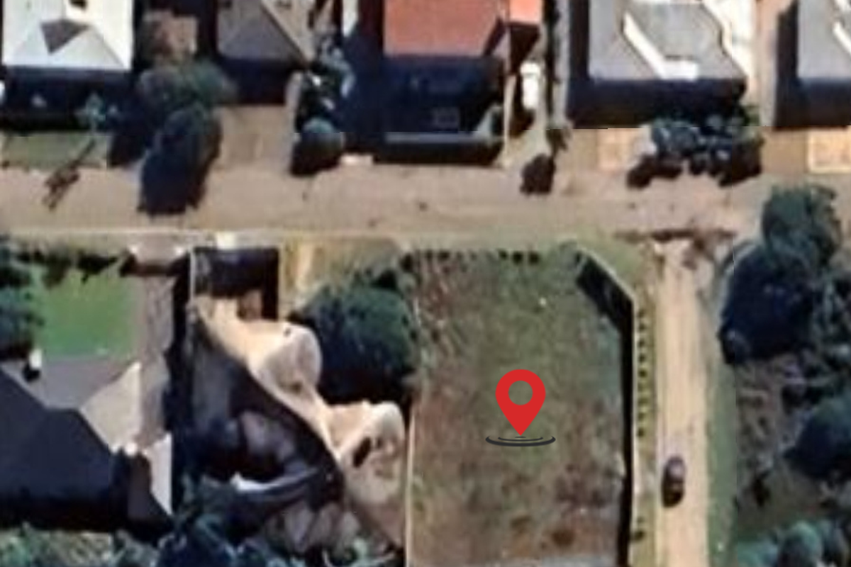 An aerial view of a vacant residential plot situated within an established suburban neighborhood.