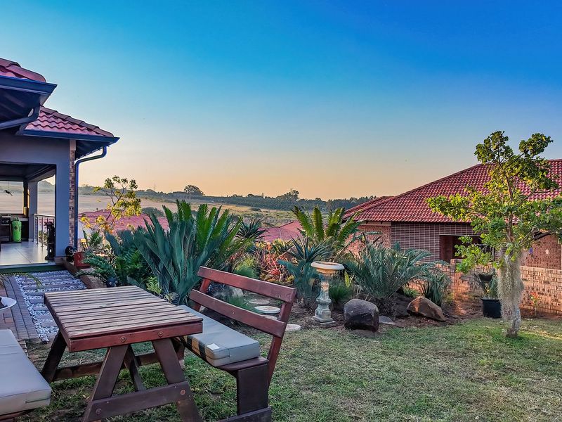 A well-maintained rear garden featuring a covered patio, brick exterior, and scenic landscape views.