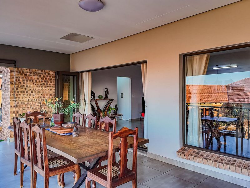 A spacious covered patio featuring tiled flooring, an exposed brick feature wall, and large sliding doors providing seamless access to the interior living area.