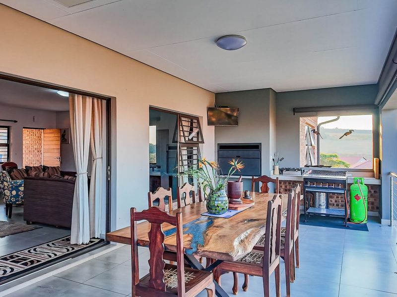 Spacious covered patio featuring a built-in braai, tiled flooring, and seamless flow to the interior living area, perfect for outdoor entertaining.
