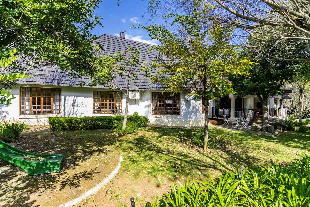 Rear view of the house featuring a tiled roof, timber-framed windows, and a spacious garden with a covered patio area.