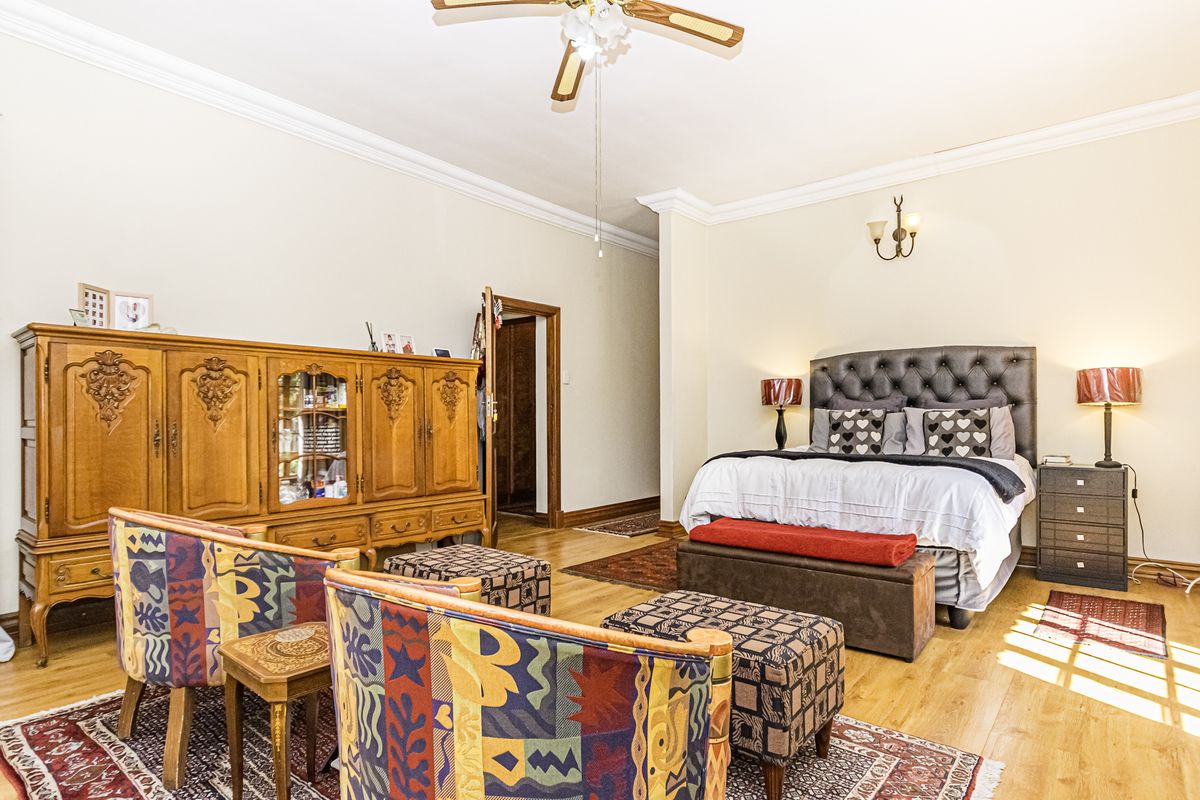 Spacious bedroom featuring hardwood flooring, crown molding, and a ceiling fan, offering a comfortable and well-maintained living space.