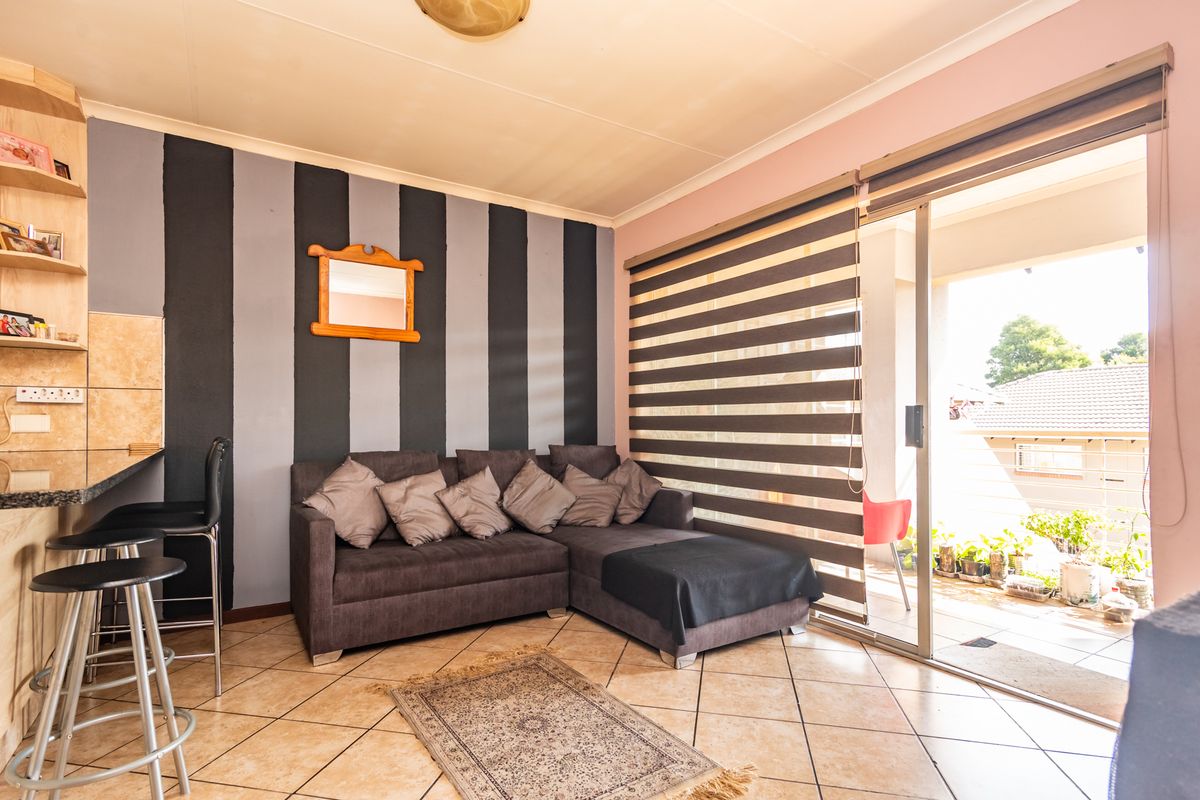 A living room featuring tiled flooring, built-in shelving, and a sliding glass door providing access to an outdoor patio area.
