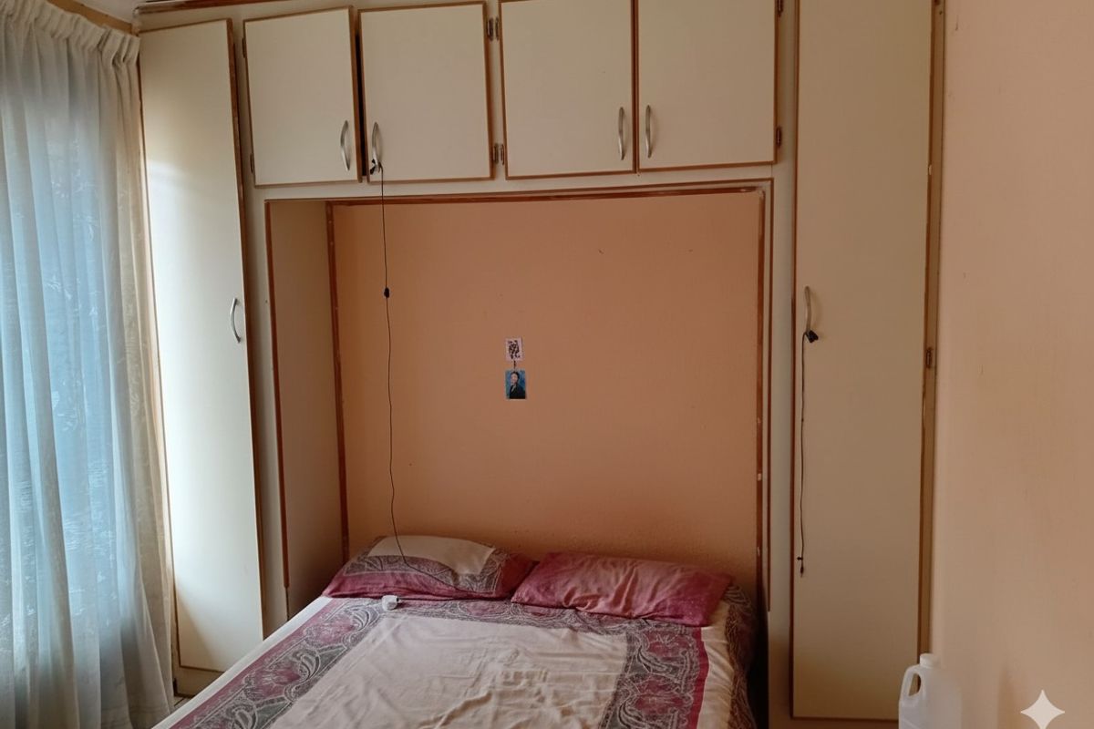 A bedroom featuring built-in cupboards with overhead storage cabinets, providing functional storage space within the room.