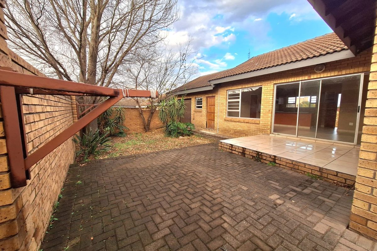 Rear exterior view featuring a paved patio area, brick boundary walls, and access to the interior living space through sliding glass doors.