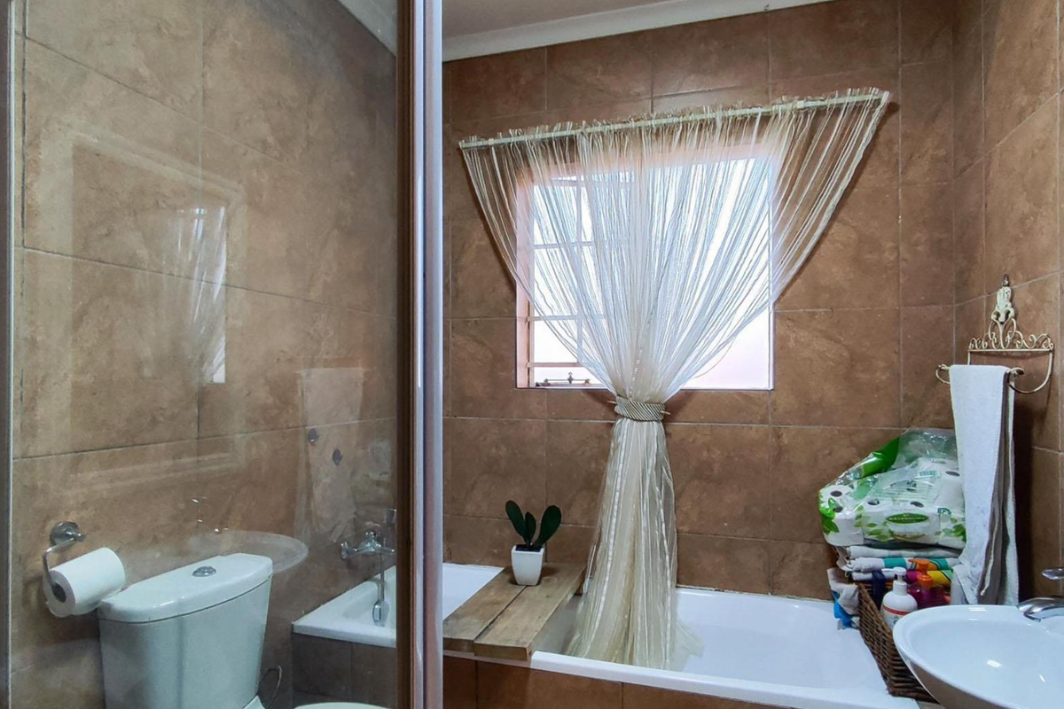A functional bathroom featuring a shower enclosure, bathtub, washbasin, and full-height wall tiling.