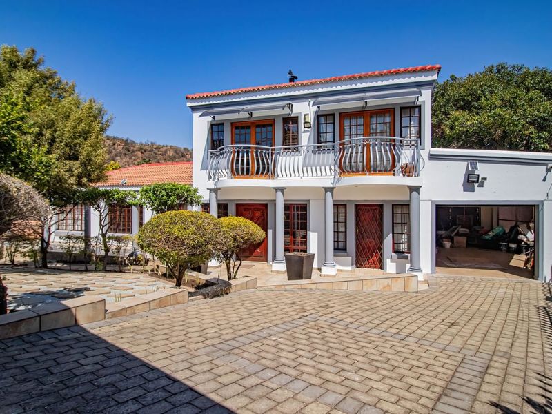 A two-story residential property featuring a paved driveway, double garage, and an upper-level balcony with decorative metal railings.