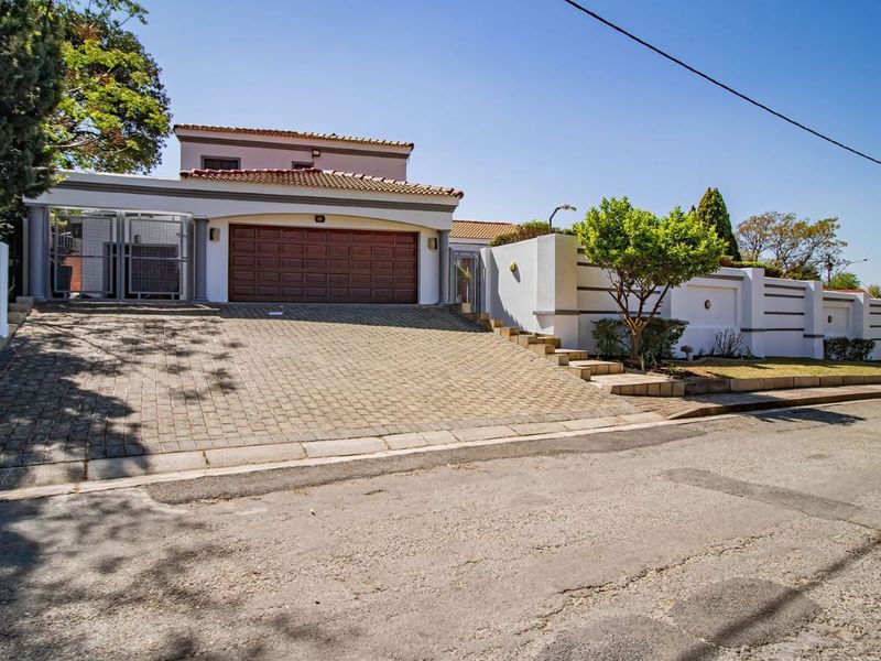 Front elevation of a residential property featuring a paved driveway, double garage, and secure boundary walling.