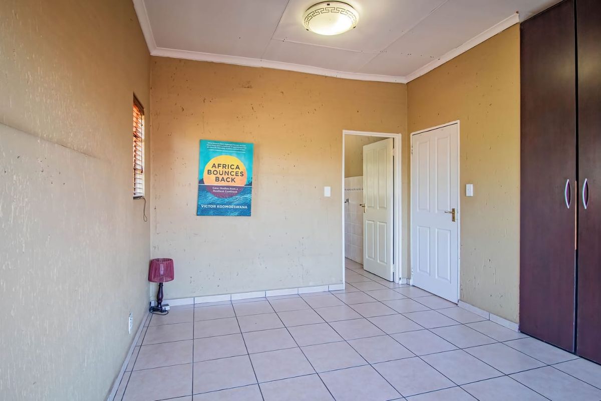 A bedroom featuring tiled flooring, a built-in wardrobe, and neutral wall finishes, offering a blank canvas for potential updates.