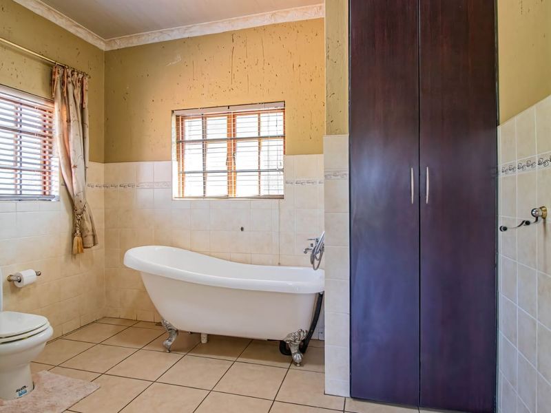 A bathroom featuring a classic clawfoot bathtub, built-in storage cabinetry, and tiled finishes, requiring cosmetic updates to the wall surfaces.