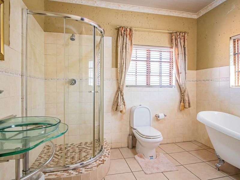A functional bathroom featuring a curved glass shower enclosure, a freestanding bathtub, and a wall-mounted basin with tiled finishes.