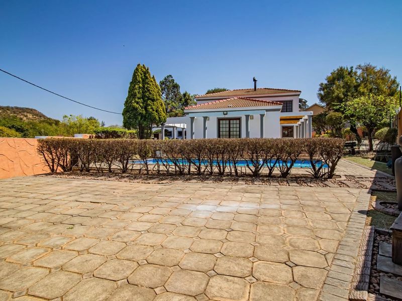 Rear exterior view featuring a swimming pool, paved patio area, and established garden boundaries with a tiled roof house structure.