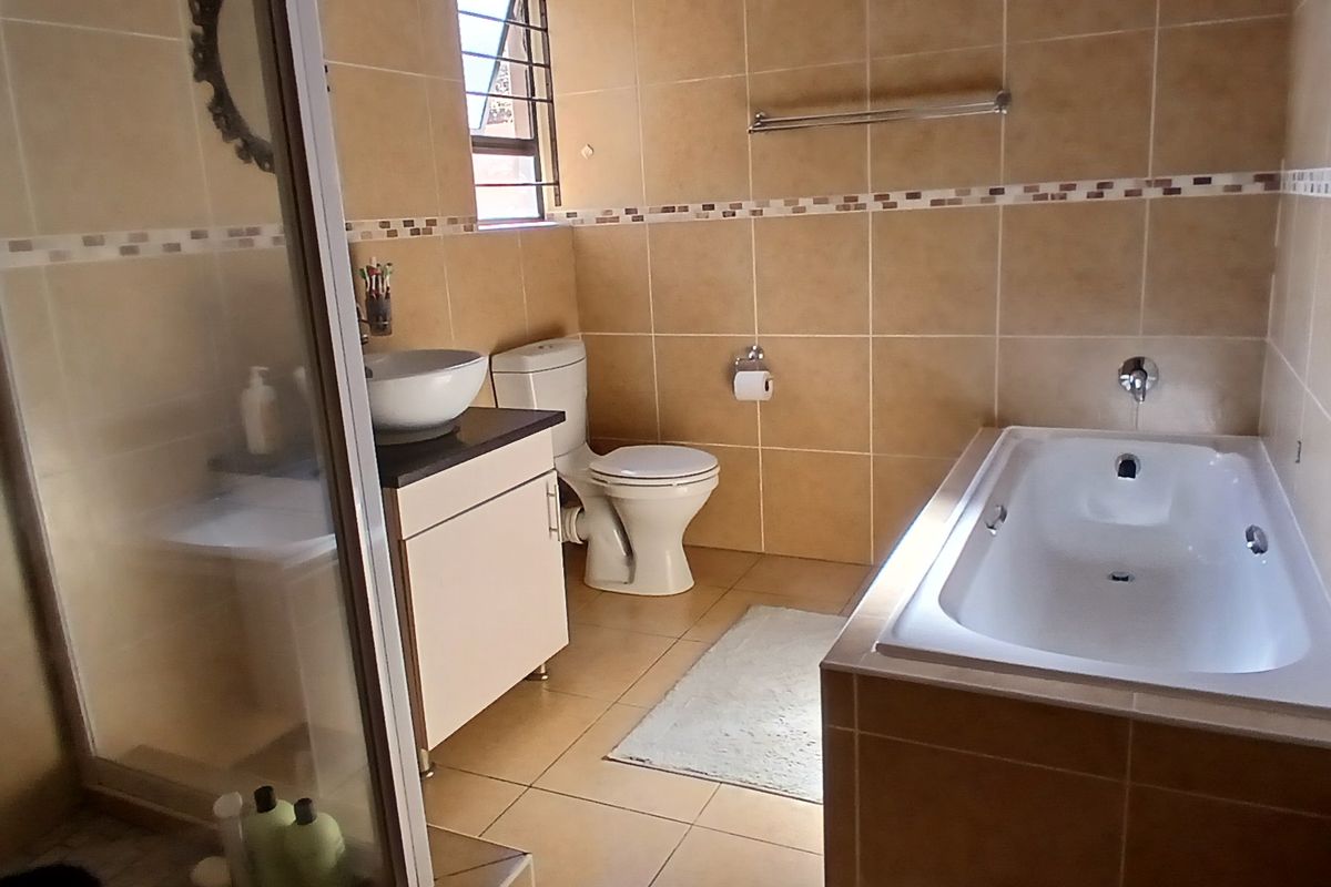 A functional bathroom featuring a tiled shower enclosure, a built-in bathtub, a vanity with a vessel sink, and a toilet.