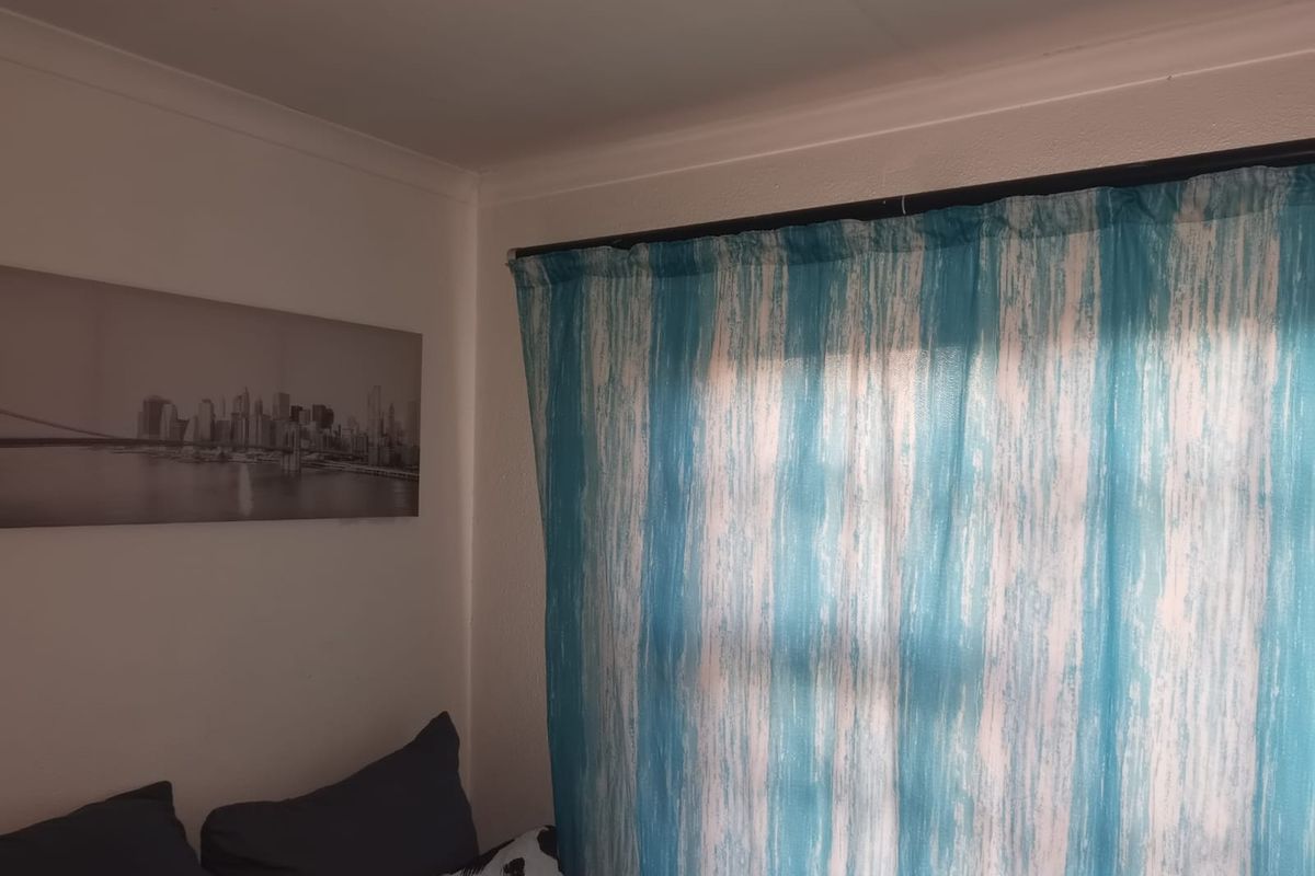 A bedroom corner featuring a window with a curtain rod and decorative coving along the ceiling line.
