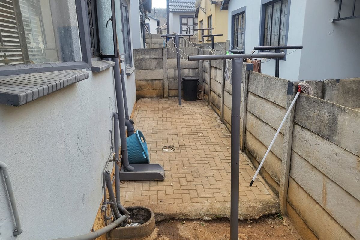 A narrow paved rear courtyard area featuring precast concrete boundary walls and a fixed washing line, providing functional outdoor utility space.