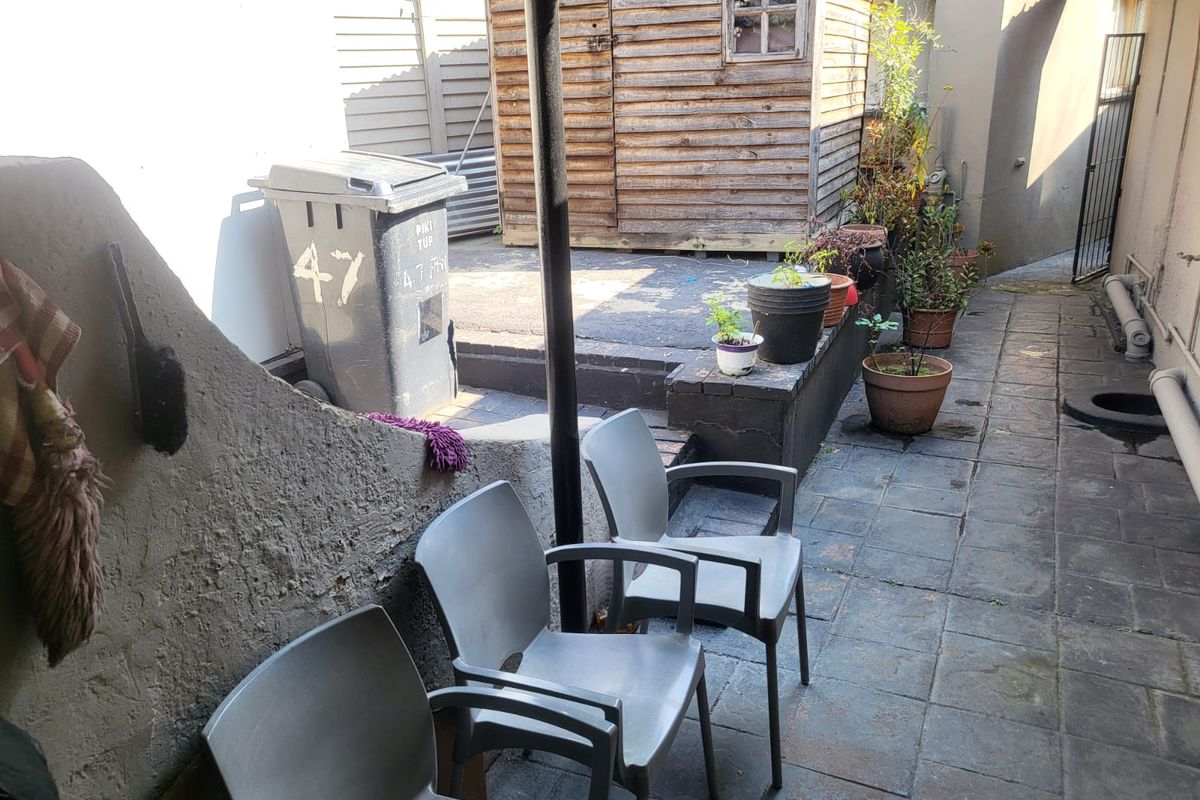 A paved rear courtyard area featuring a retaining wall and a timber garden shed, providing functional outdoor utility space.