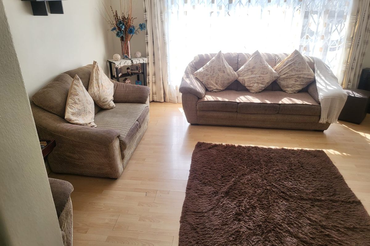A bright living room featuring light-toned laminate flooring and a large window allowing for ample natural light.