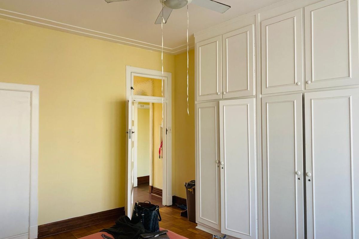 Bedroom featuring built-in white cabinetry, parquet flooring, and a ceiling fan, offering a functional space with classic architectural details.