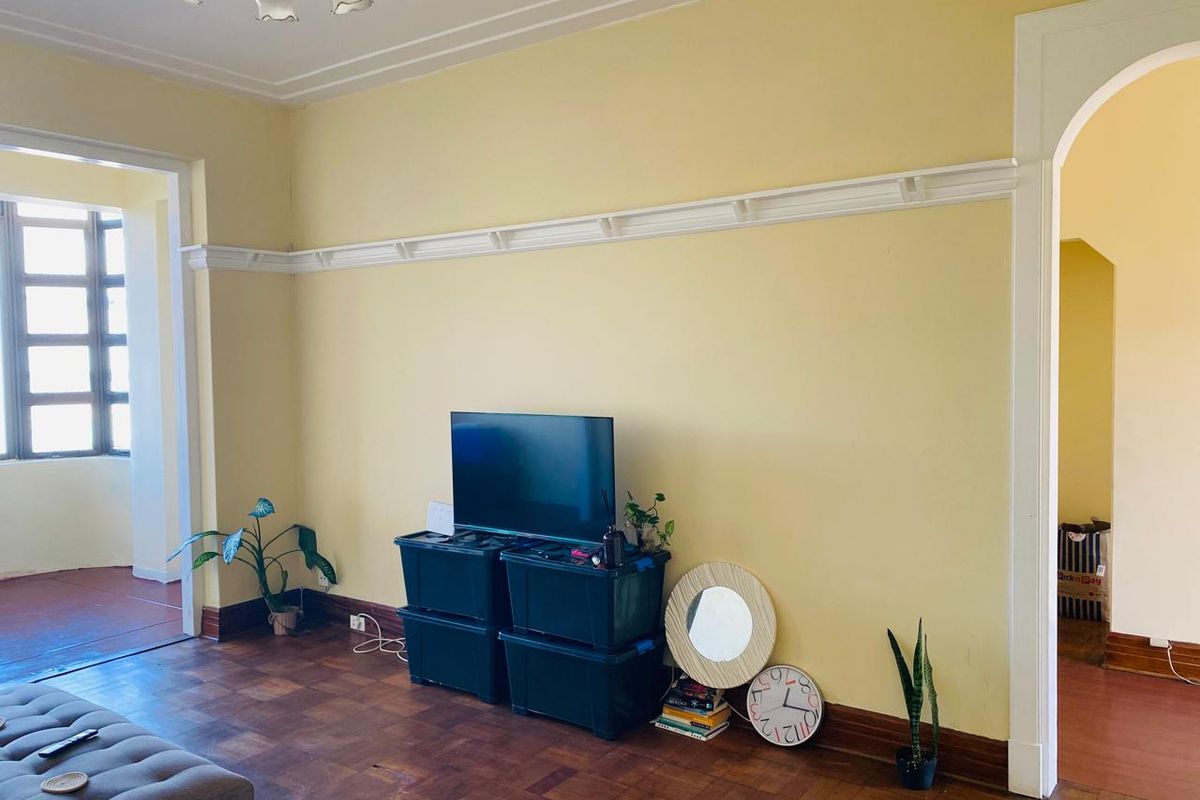 Living room featuring original parquet flooring, decorative picture rails, and a classic archway leading to adjacent spaces.