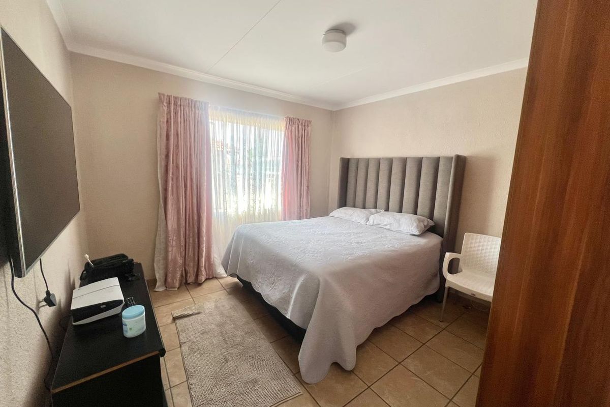 A functional bedroom featuring tiled flooring, neutral wall finishes, and a built-in wardrobe, offering a comfortable and practical living space.